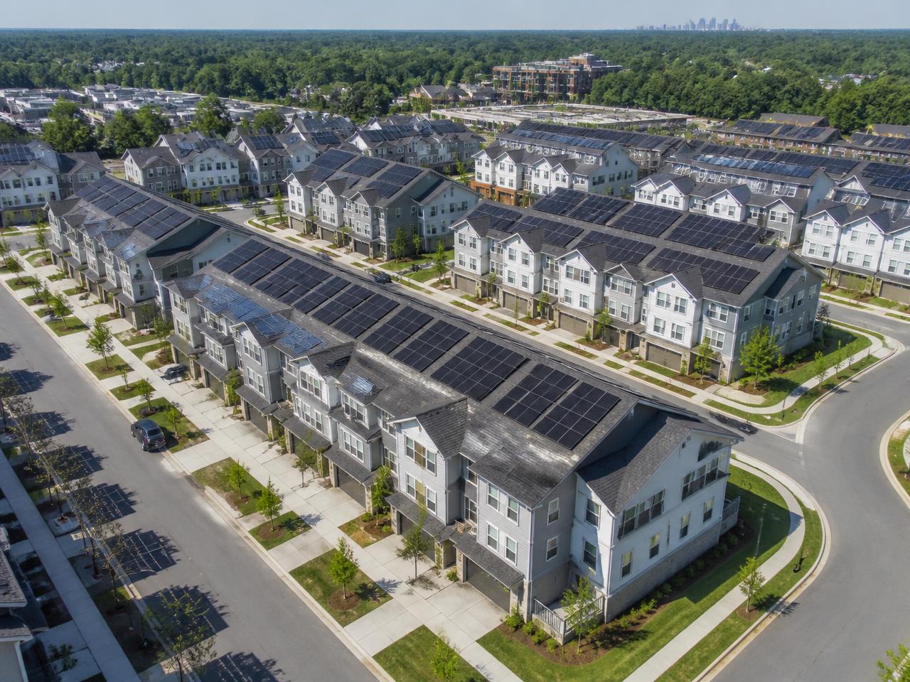 Aerial view of a build-to-rent townhome community with solar panels on each roof